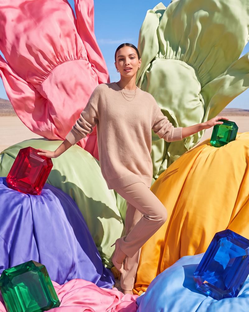 Fabi standing among giant silk folds and oversized gems in the desert